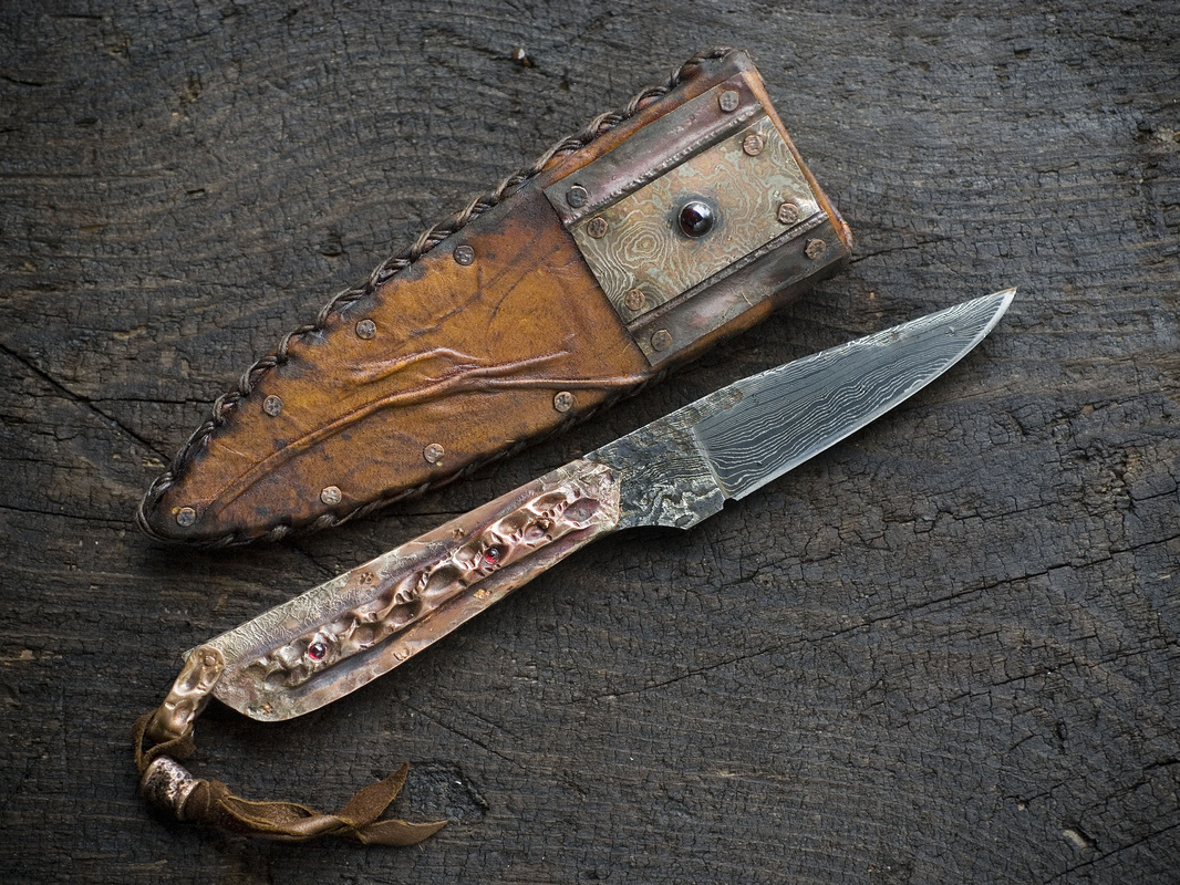 John M. Cohea, Nettleton, MS, U.S. “Vest Knife” (8 in x 2 in) (20.3 cm x 5 cm)  Damascus steel, copper, fused silver, mokume gane, garnets, leather, rawhide, photo by Scott A. Roush -- www.foldforming.org